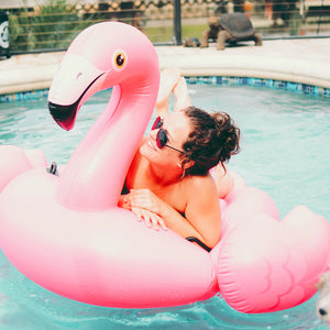 Tan woman in the pool with a flamingo floaty! Click to find us on Instagram.